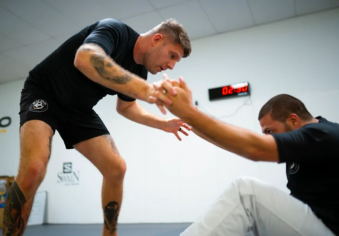 Charlie Vinch coaching an adult student through a standing grappling drill at Budo Martial Arts